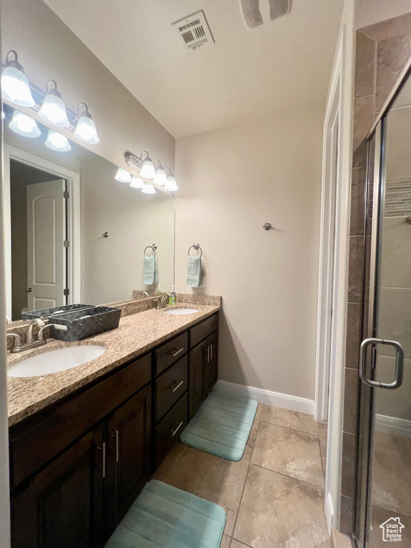 Bathroom with a shower with door, vanity, and tile patterned floors