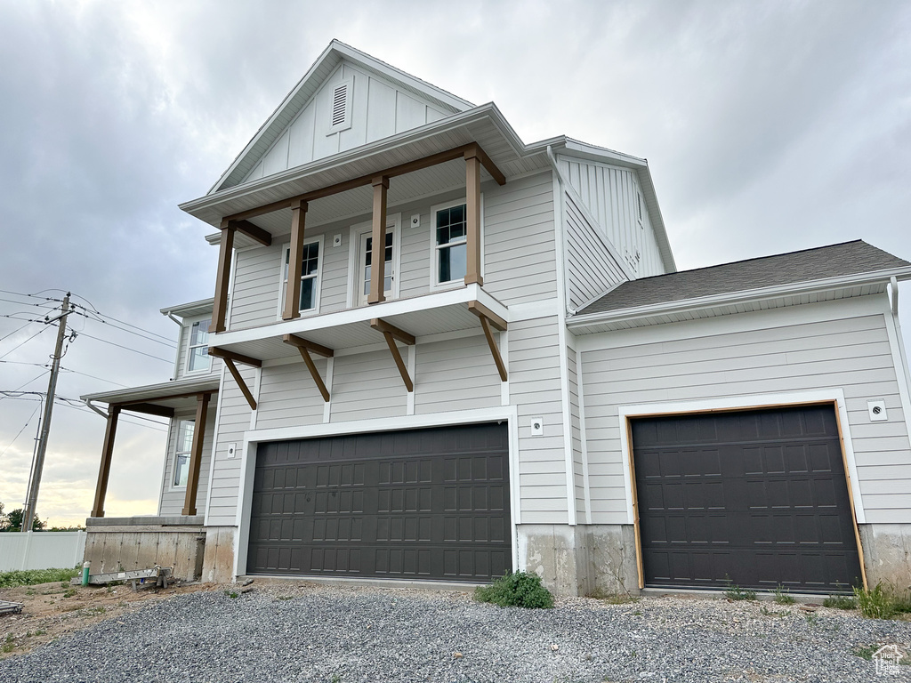 View of front of home with a garage, board and batten siding, and gravel driveway