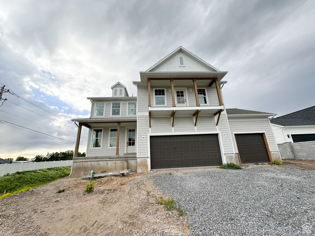 View of front of house with covered porch, driveway, fence, and an attached garage