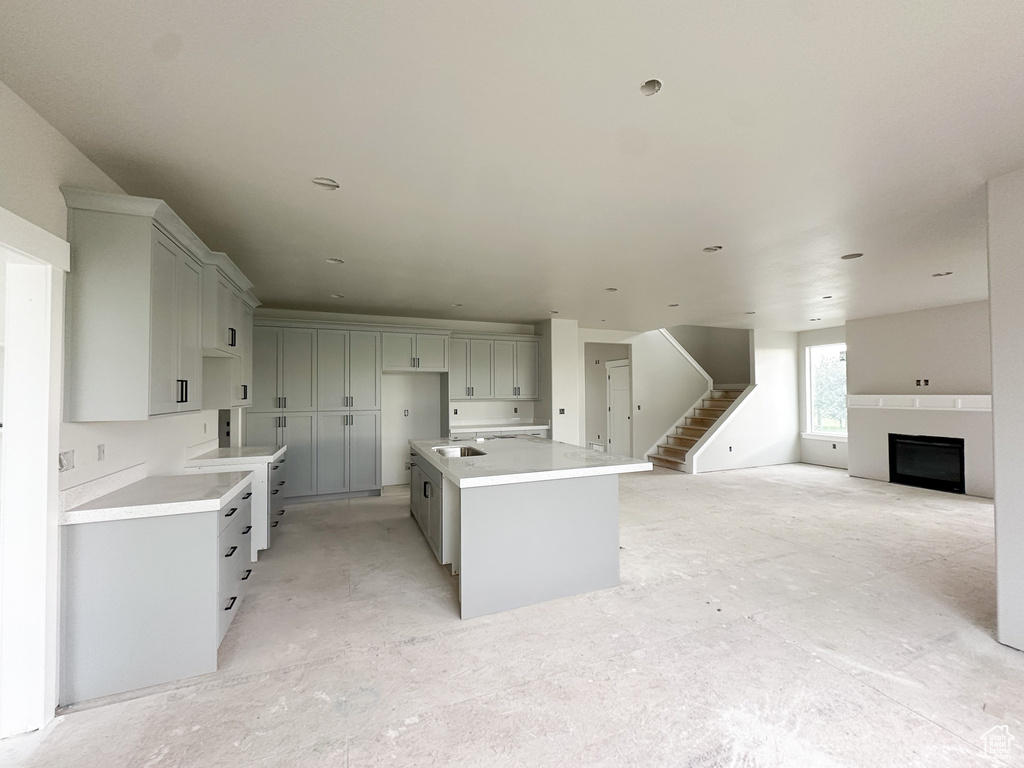 Kitchen featuring a fireplace, a kitchen island, gray cabinets, and open floor plan