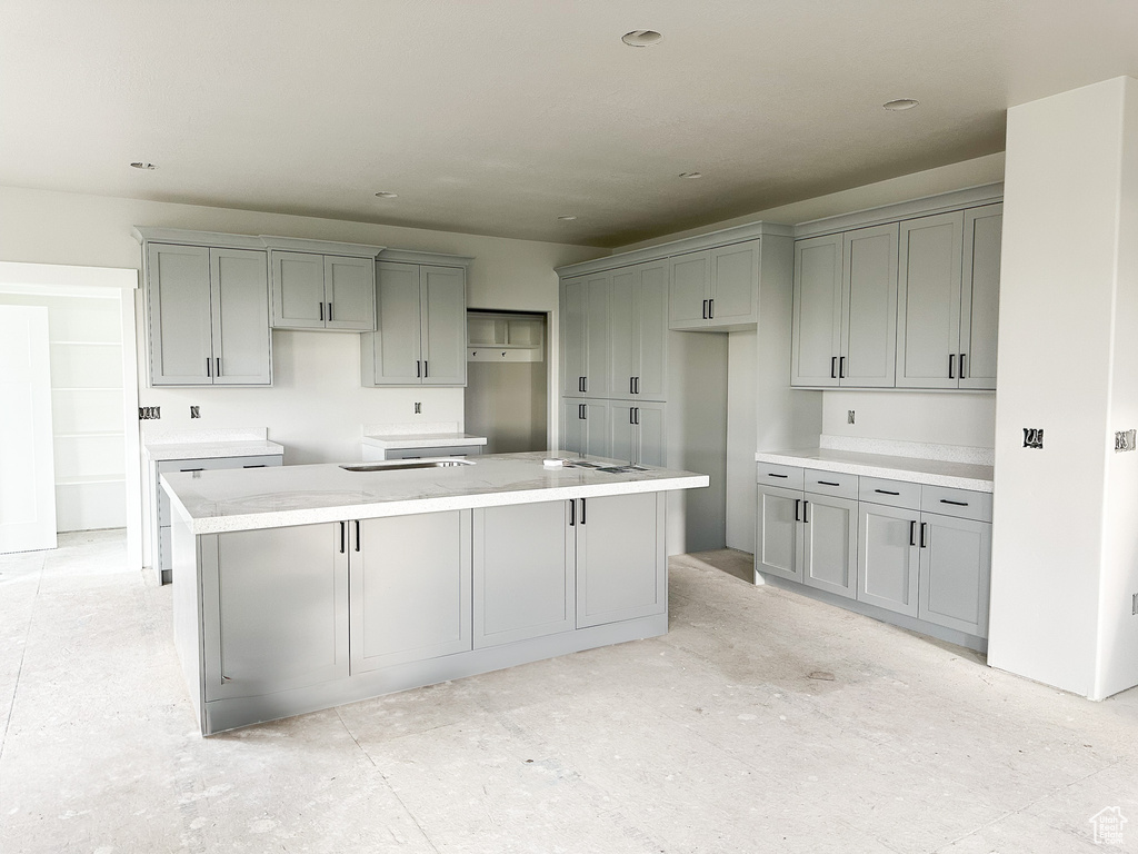 Kitchen with gray cabinets, a kitchen island, and a sink