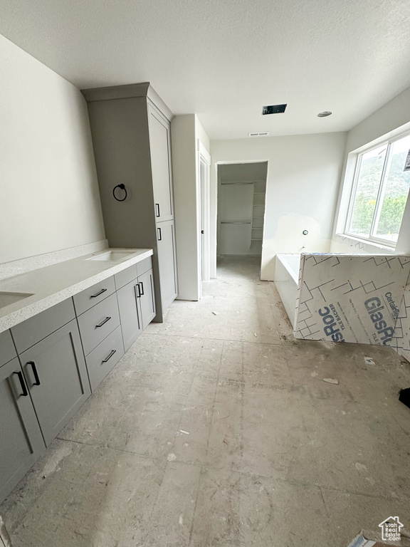 Bathroom with a bath, a textured ceiling, and vanity
