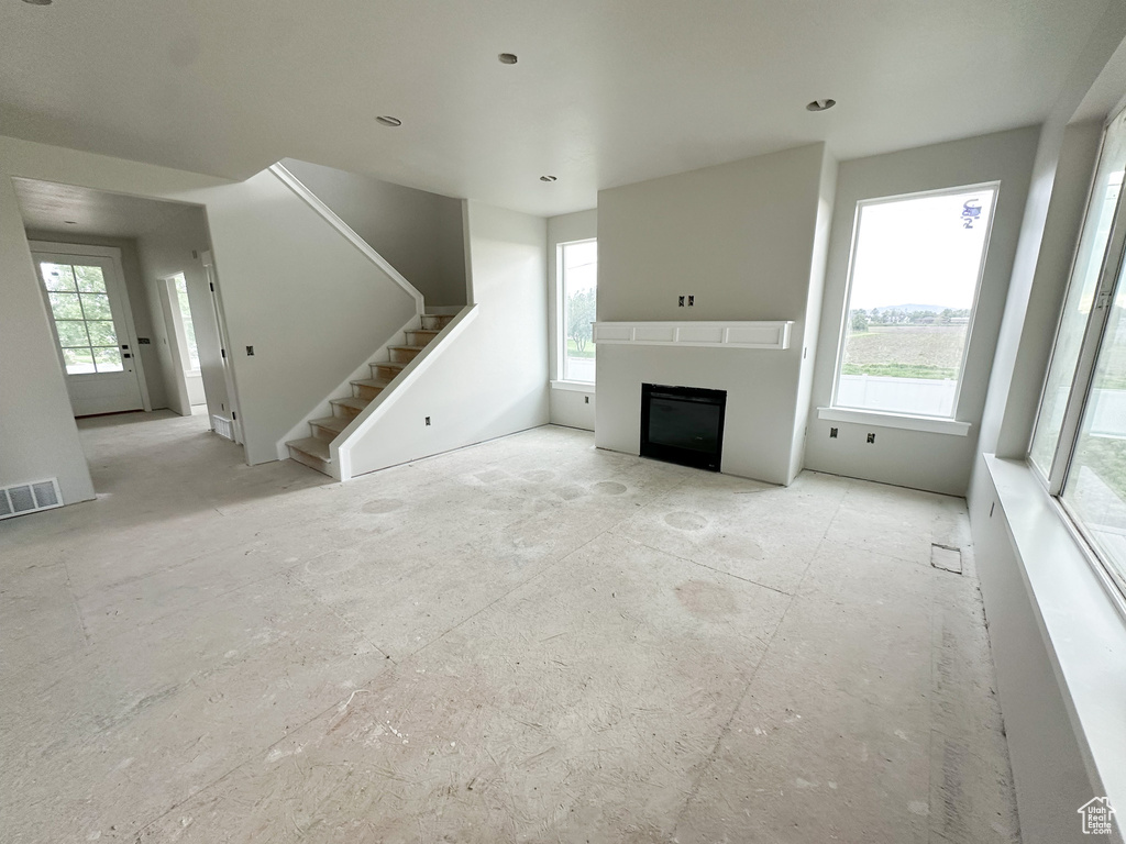 Unfurnished living room with healthy amount of natural light, a fireplace, and stairs