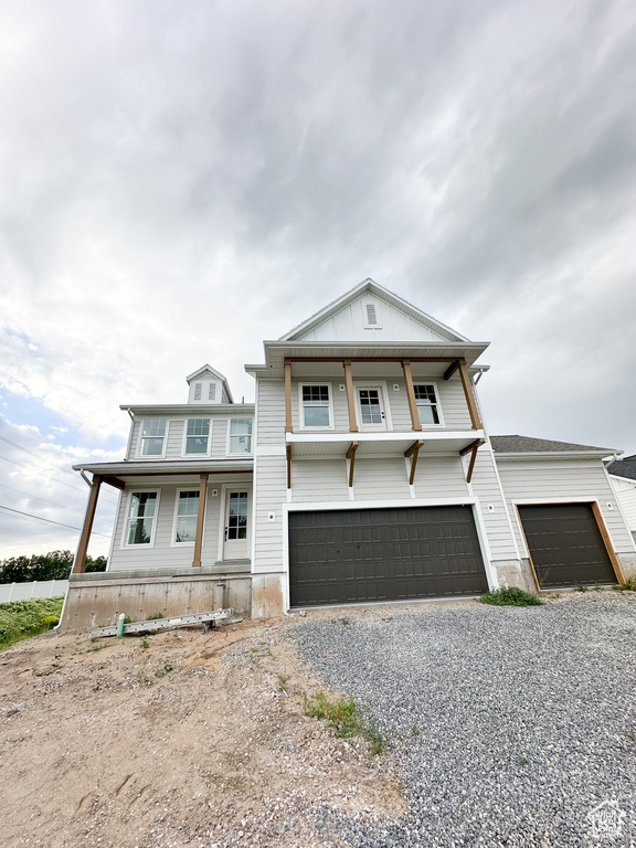 View of front of house with a porch, gravel driveway, and a garage