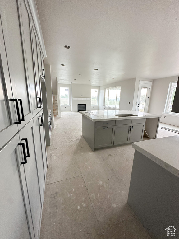 Kitchen with open floor plan, a center island, a fireplace, gray cabinets, and light countertops