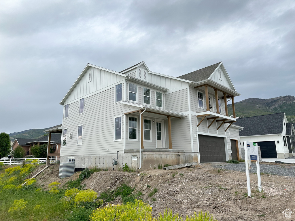 View of side of home featuring board and batten siding, a mountain view, fence, a garage, and central AC unit