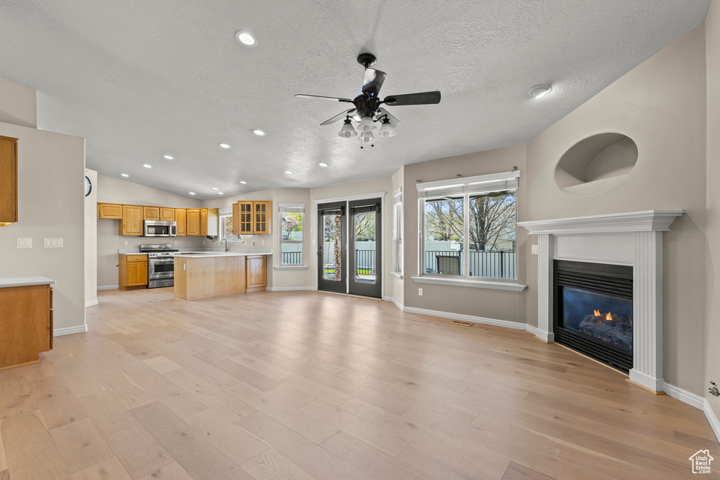 Unfurnished living room featuring baseboards, light wood-type flooring, recessed lighting, a textured ceiling, and a ceiling fan