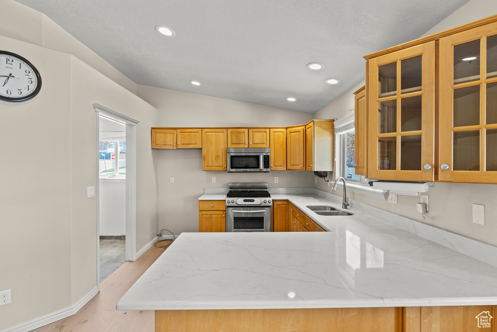 Kitchen featuring a sink, vaulted ceiling, stainless steel appliances, and a wealth of natural light