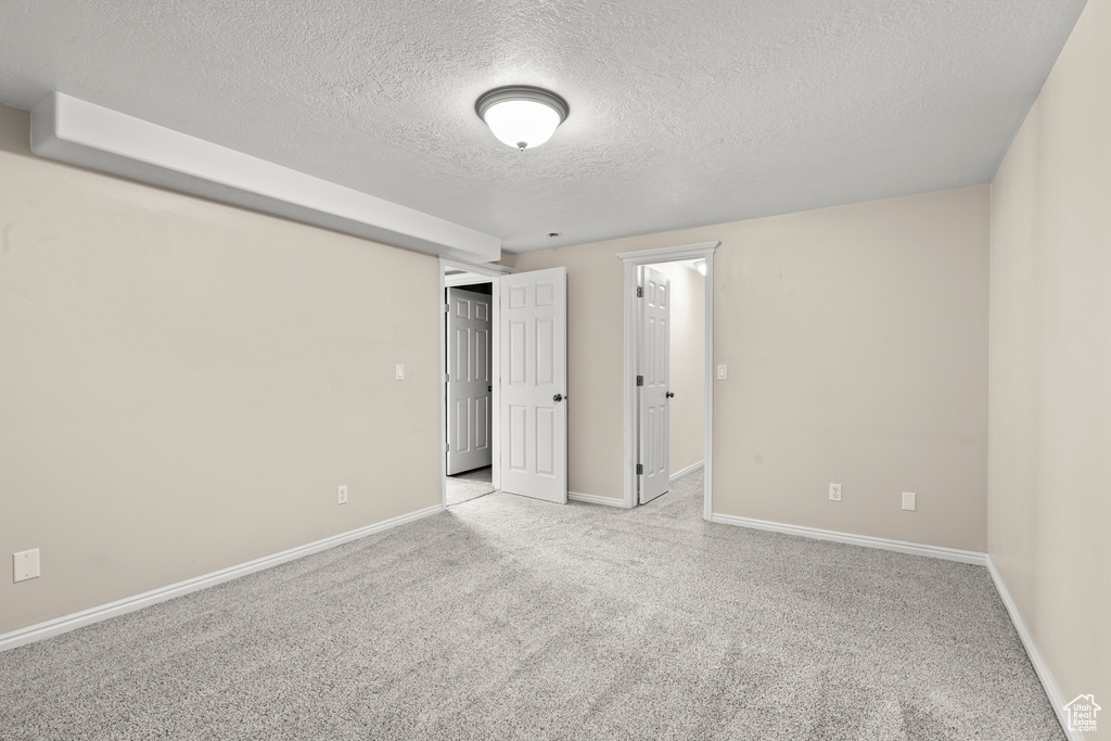 Unfurnished bedroom with a textured ceiling, baseboards, and carpet