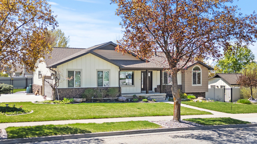 View of front of property with board and batten siding, fence, and a front yard