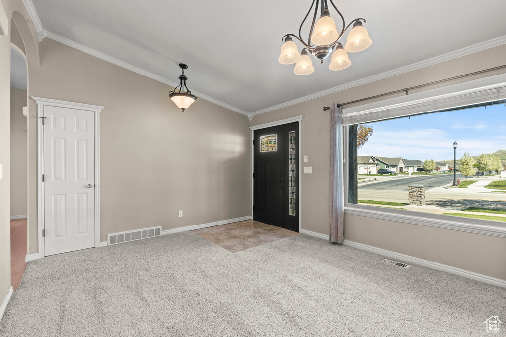 Foyer featuring an inviting chandelier, ornamental molding, carpet, and visible vents
