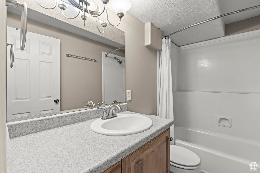 Full bathroom with shower / bath combo with shower curtain, toilet, a textured ceiling, and vanity