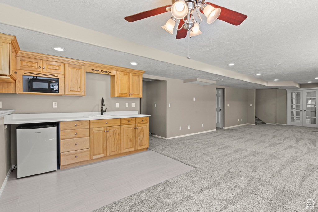 Kitchen with black microwave, baseboards, a textured ceiling, and light countertops