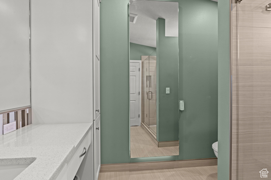Bathroom with vanity, baseboards, toilet, and a shower stall