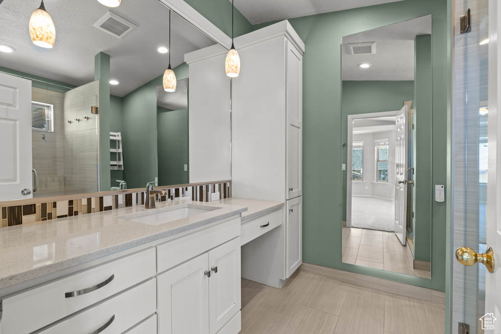 Bathroom with visible vents, recessed lighting, vanity, and tiled shower