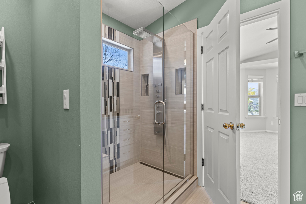 Full bath with baseboards, a wealth of natural light, toilet, and a shower stall