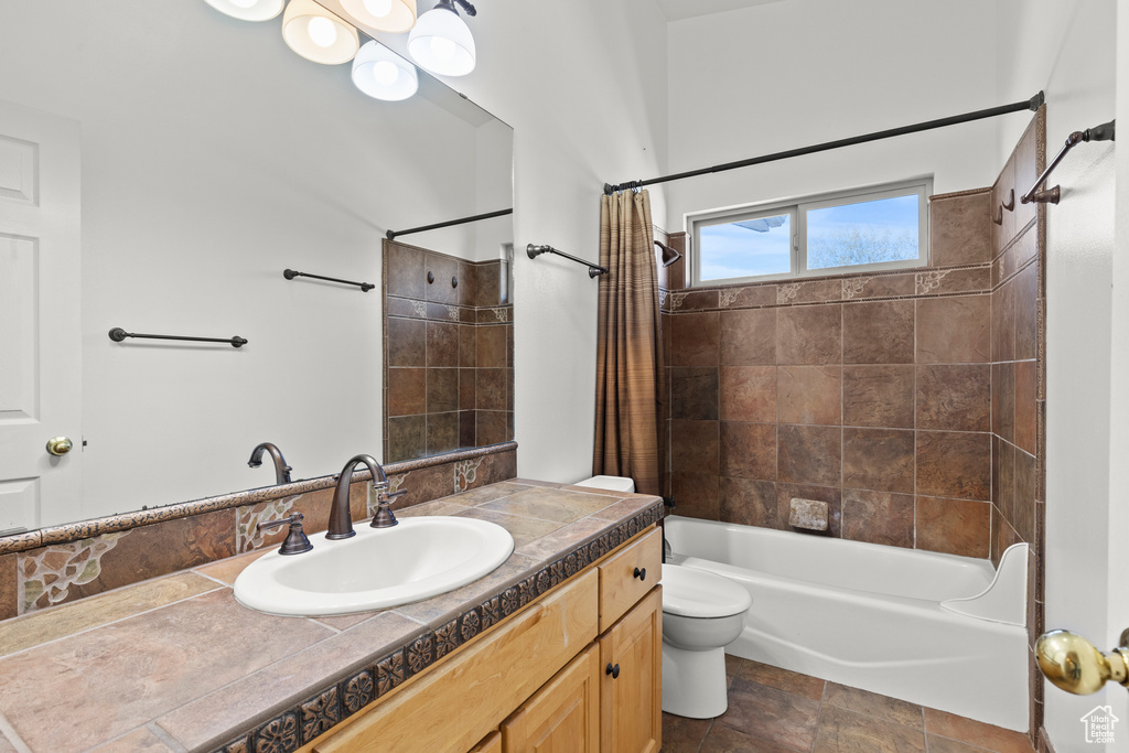 Bathroom featuring shower / bath combo with shower curtain, stone finish flooring, toilet, and vanity
