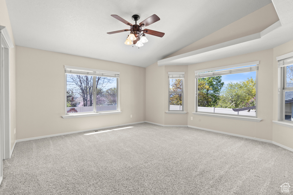 Unfurnished room with carpet flooring, plenty of natural light, and lofted ceiling