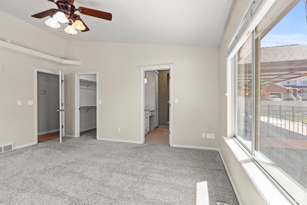 Unfurnished bedroom with carpet floors, visible vents, baseboards, access to outside, and vaulted ceiling
