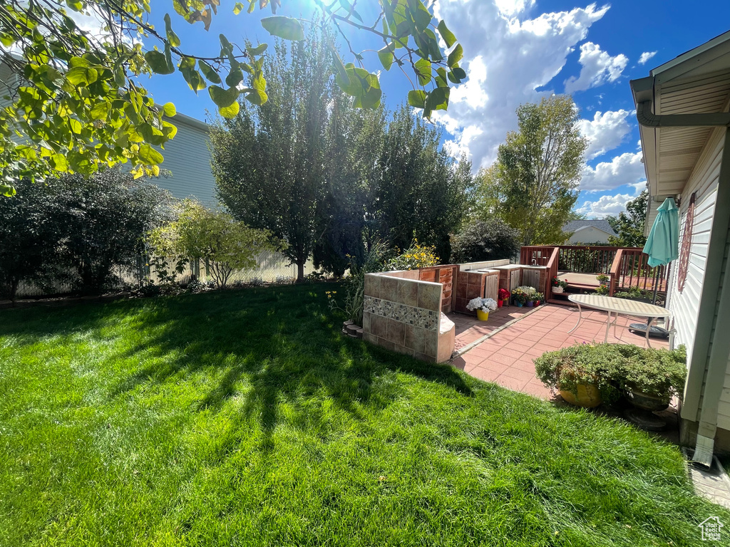 View of yard with a wooden deck and a patio