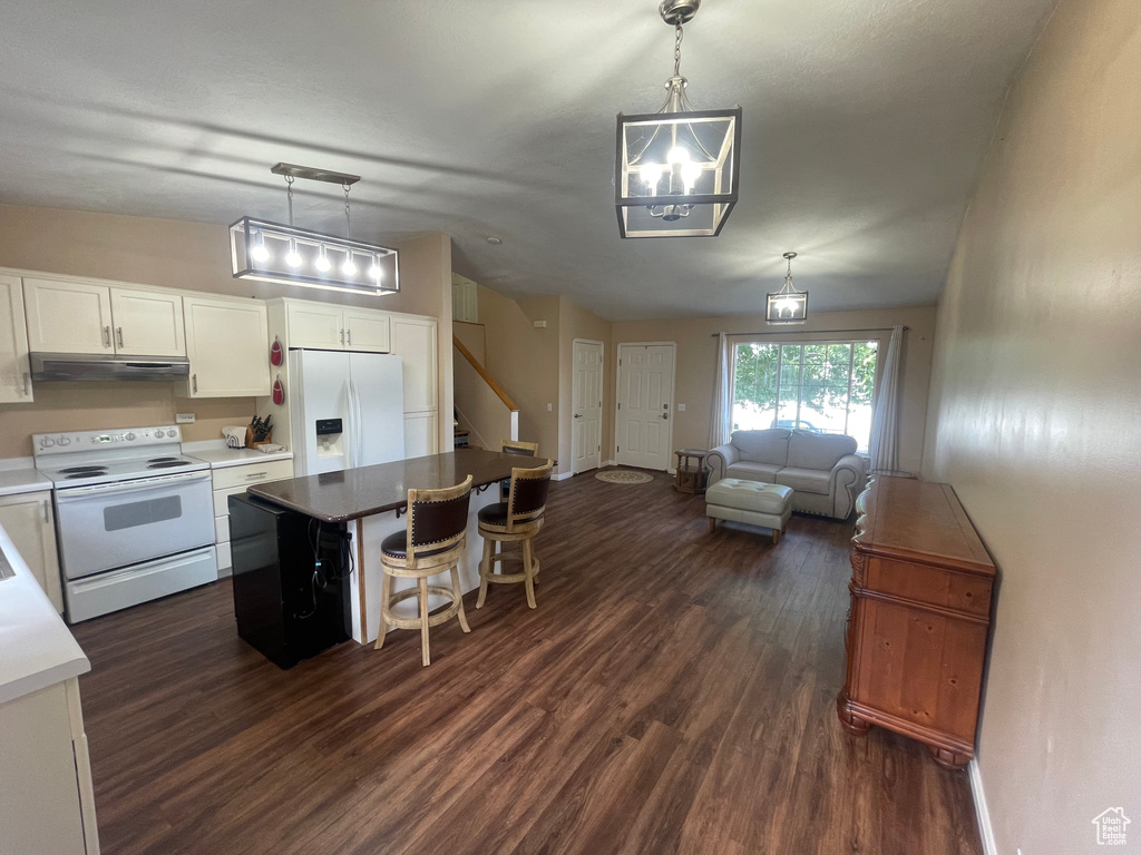 Kitchen with white cabinetry, dark wood-type flooring, a kitchen island, and white appliances