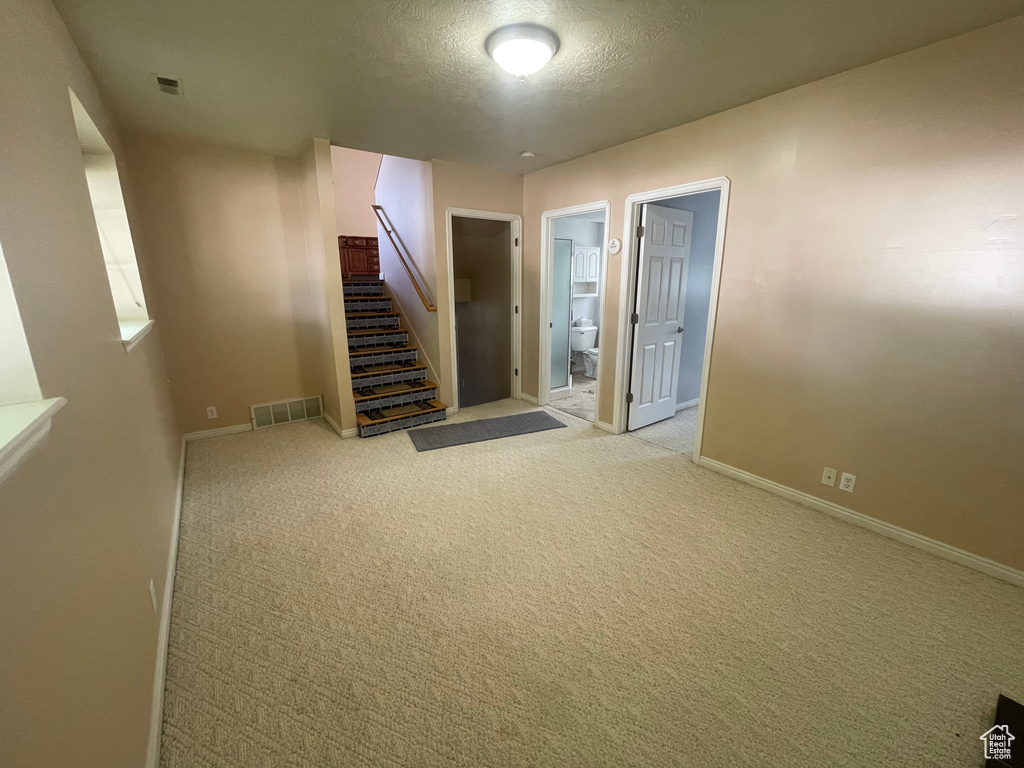 Interior space featuring a textured ceiling and light carpet
