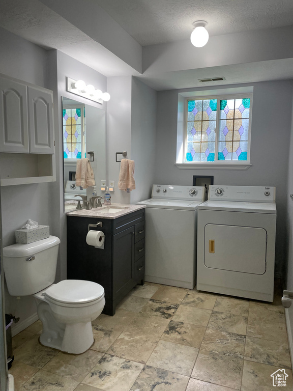 Bathroom with toilet, tile patterned floors, washer and clothes dryer, and vanity