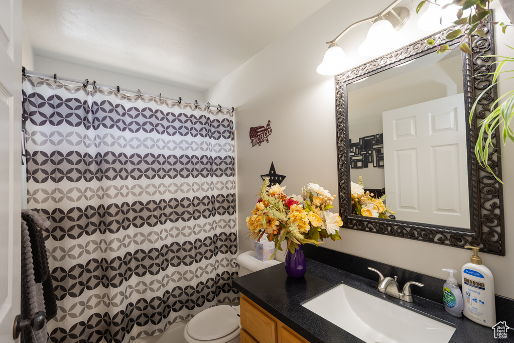 Bathroom with toilet, vanity, and curtained shower