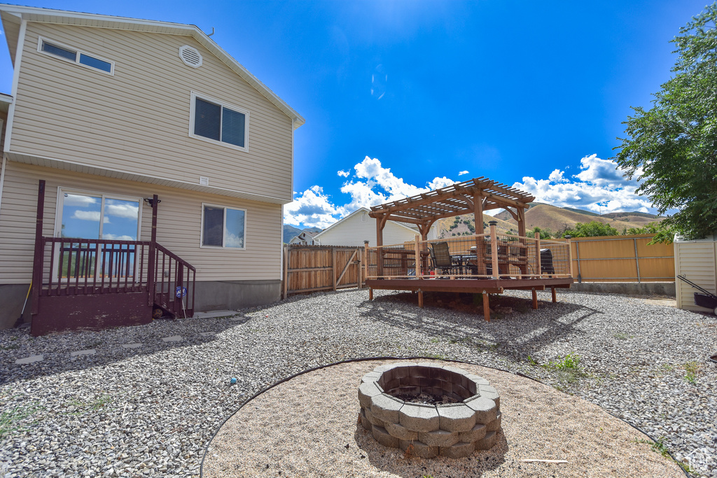 Back of house with an outdoor fire pit, a pergola, and a wooden deck