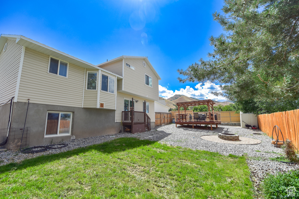 Rear view of property with a gazebo, a fire pit, and a yard