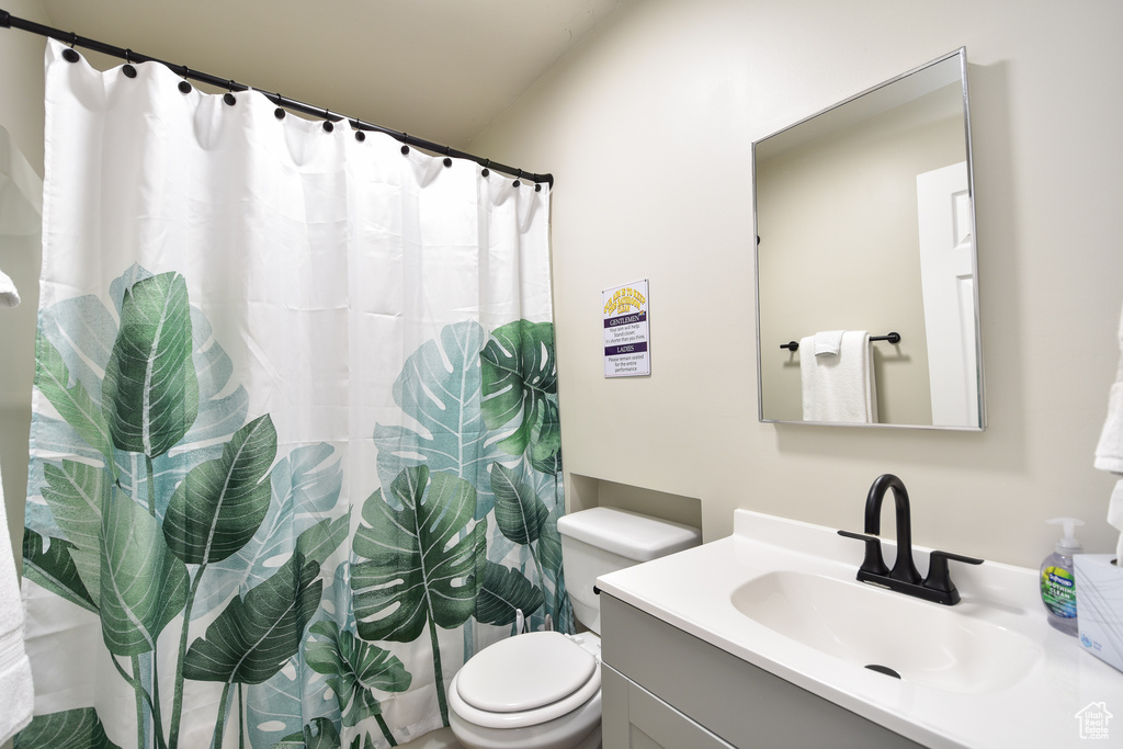 Bathroom featuring toilet, walk in shower, and vanity