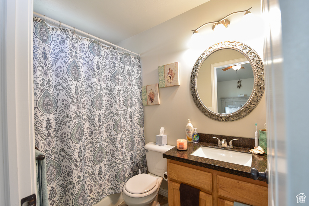 Bathroom with toilet, vanity, and curtained shower