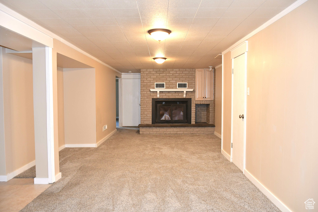 Unfurnished living room with ornamental molding, a brick fireplace, and light carpet