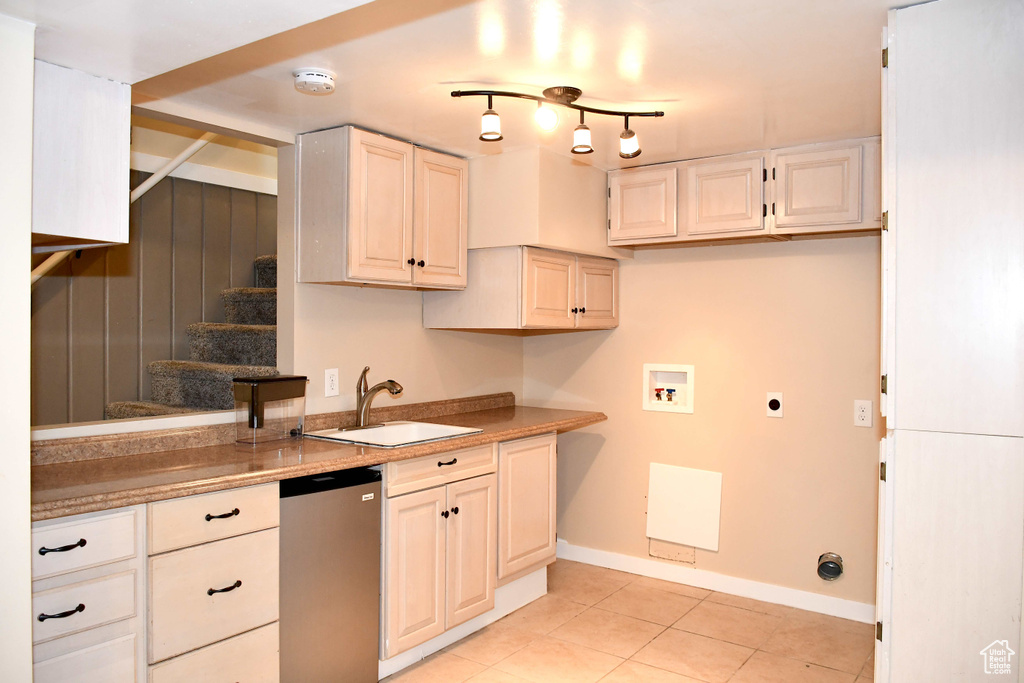 Kitchen with sink, stainless steel dishwasher, rail lighting, and light tile patterned floors