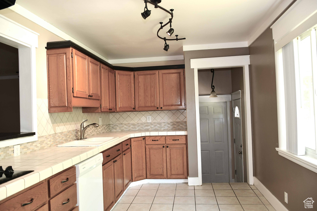 Kitchen with sink, backsplash, white dishwasher, and light tile patterned floors