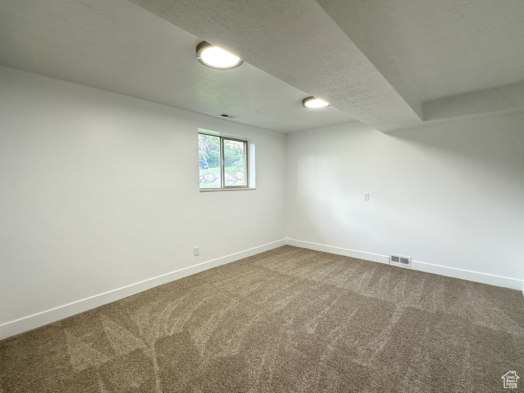 Empty room with a textured ceiling and carpet flooring