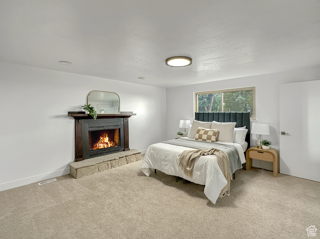 Carpeted bedroom with a stone fireplace