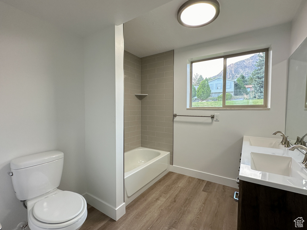 Full bathroom featuring tiled shower / bath combo, hardwood / wood-style flooring, toilet, and vanity