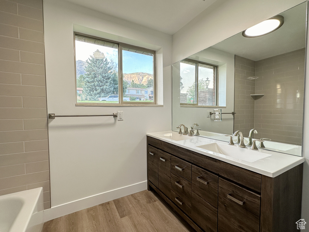 Bathroom with hardwood / wood-style floors, vanity, and shower / washtub combination