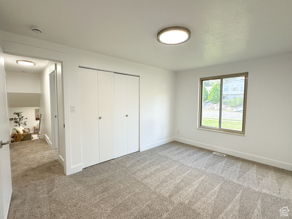 Unfurnished bedroom with a closet and light carpet