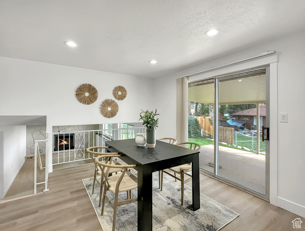 Dining area with a textured ceiling, light wood-type flooring, and a premium fireplace