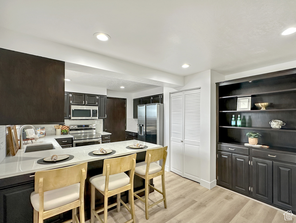 Kitchen featuring light hardwood / wood-style floors, appliances with stainless steel finishes, sink, and decorative backsplash