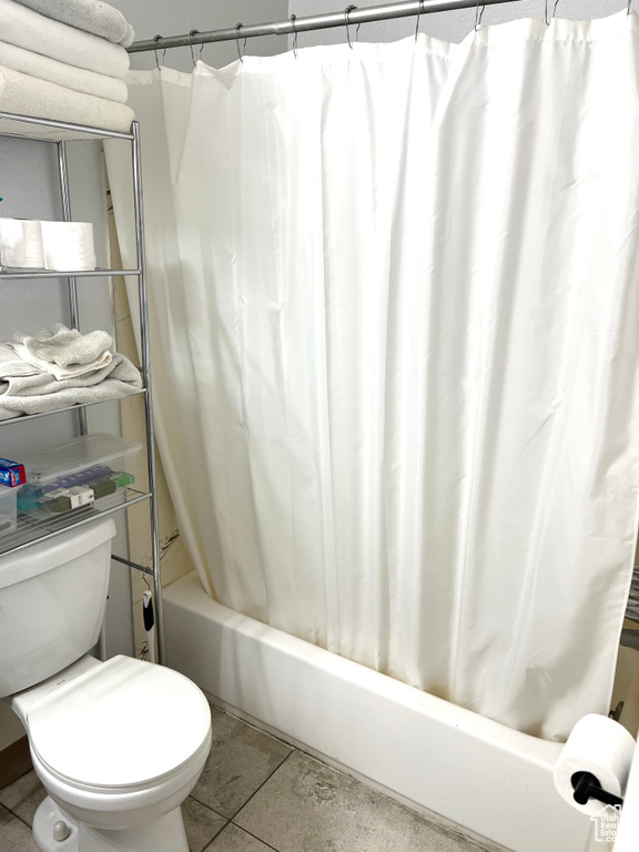 Bathroom featuring tile patterned floors, shower / bath combo with shower curtain, and toilet