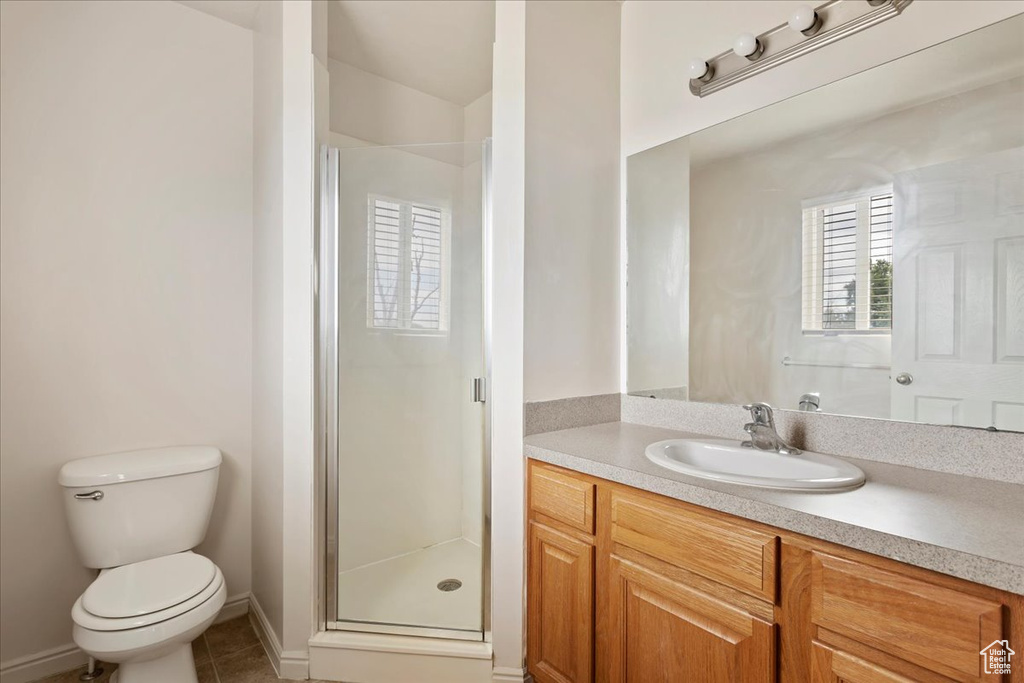 Bathroom featuring a shower with shower door, toilet, vanity, and tile patterned floors