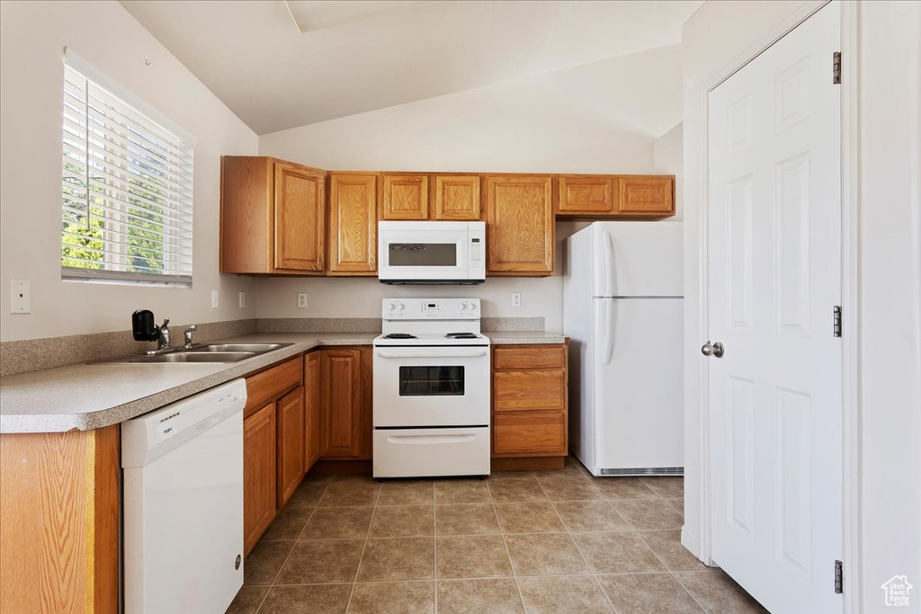 Kitchen with light tile patterned flooring, sink, white appliances, and lofted ceiling