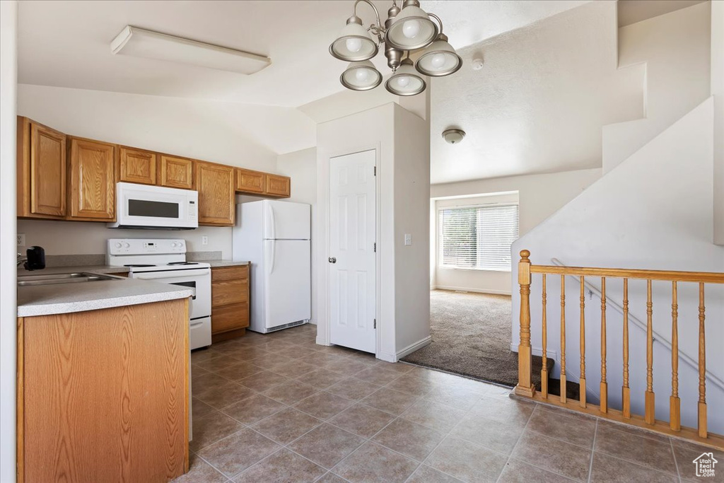 Kitchen featuring vaulted ceiling, a notable chandelier, white appliances, and dark tile patterned floors