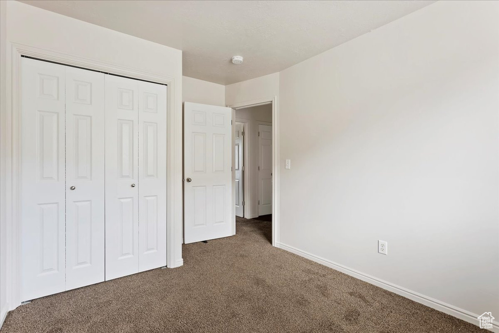 Unfurnished bedroom featuring a closet and dark carpet