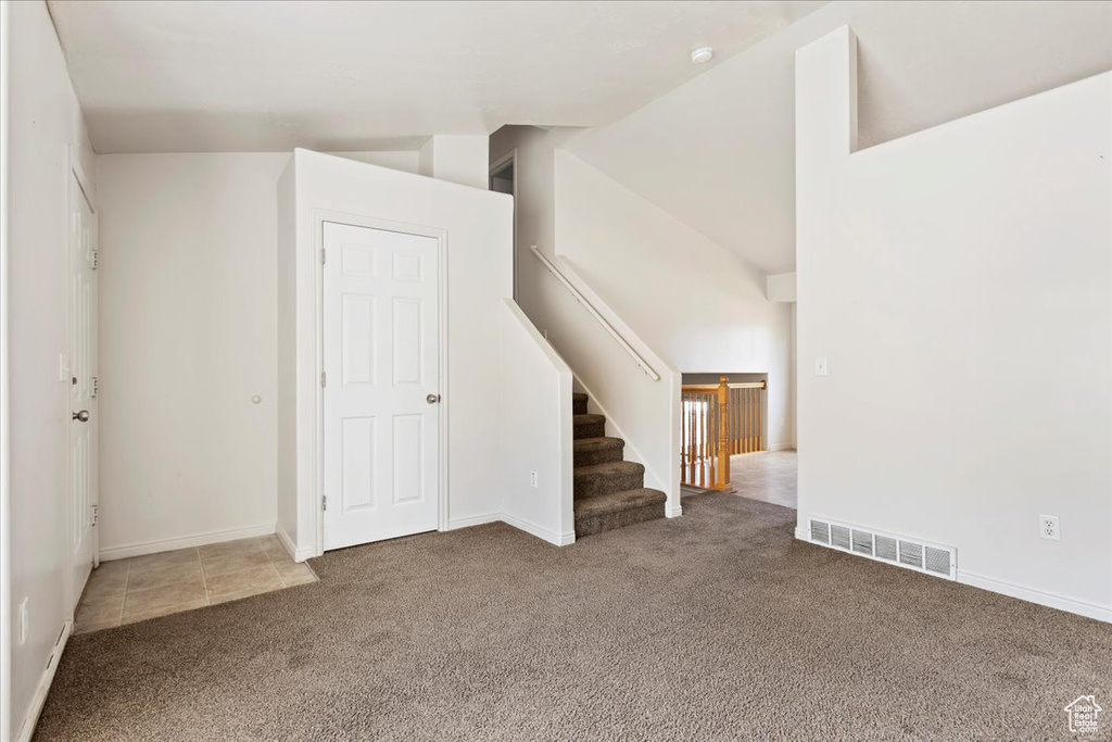 Interior space featuring carpet and high vaulted ceiling