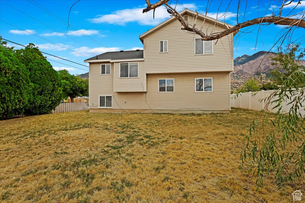 Rear view of property featuring a mountain view and a yard