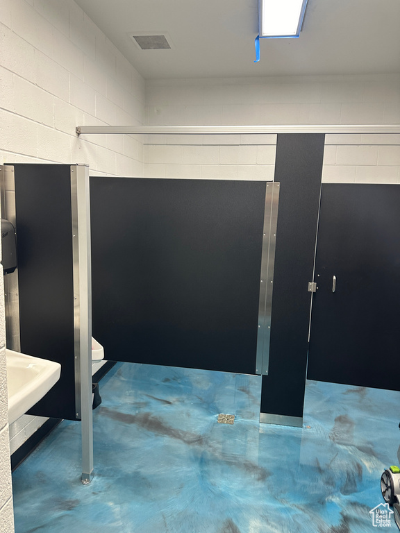 Bathroom featuring concrete floors, sink, and toilet